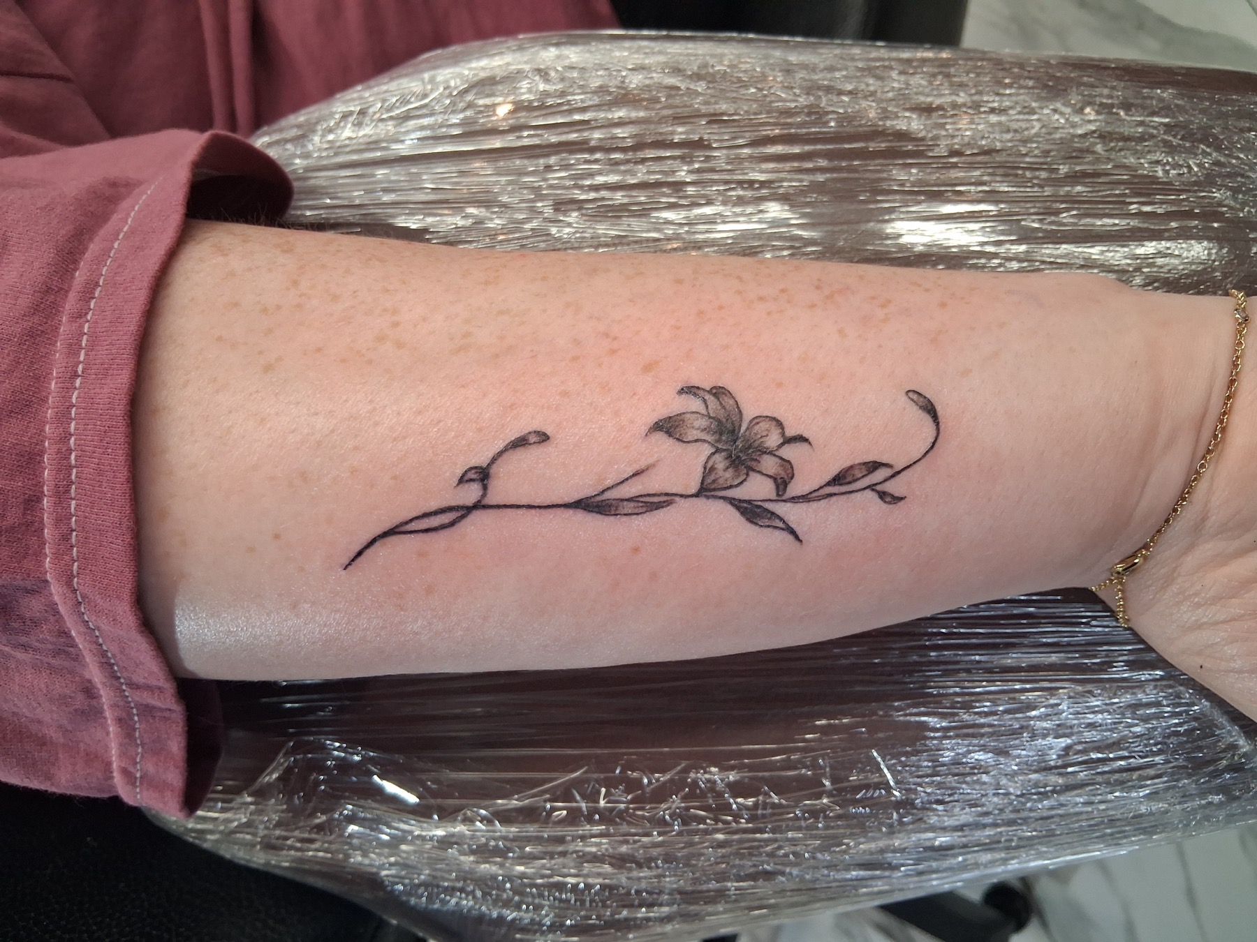 Delicate fine-line floral tattoo by Tony Parisi